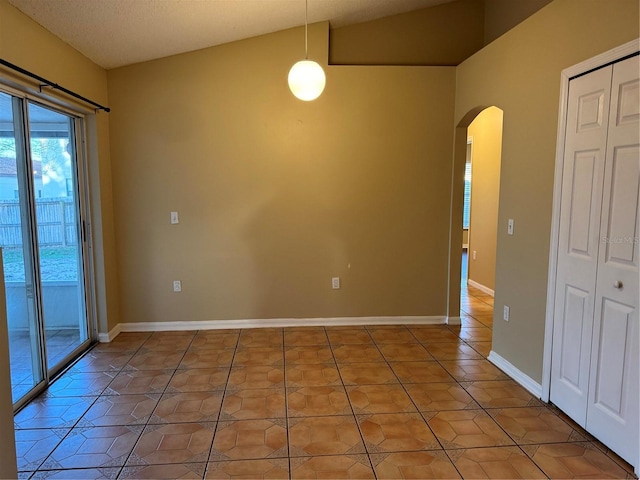 empty room featuring light tile patterned floors, baseboards, and arched walkways