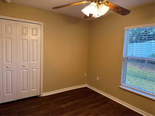 unfurnished bedroom with baseboards, ceiling fan, dark wood-type flooring, a closet, and a textured ceiling