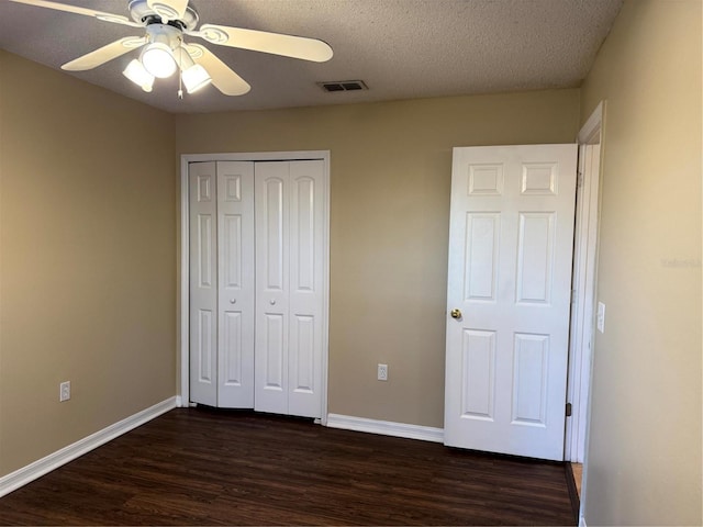 unfurnished bedroom featuring dark wood-style floors, visible vents, and baseboards