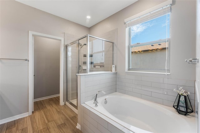 full bath with a shower stall, a garden tub, wood finished floors, and baseboards