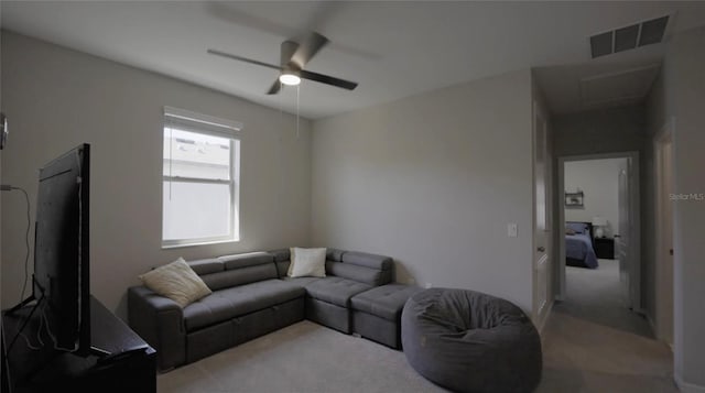 living room featuring a ceiling fan, visible vents, and light carpet