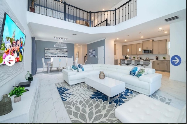 living area featuring visible vents, a high ceiling, marble finish floor, and crown molding