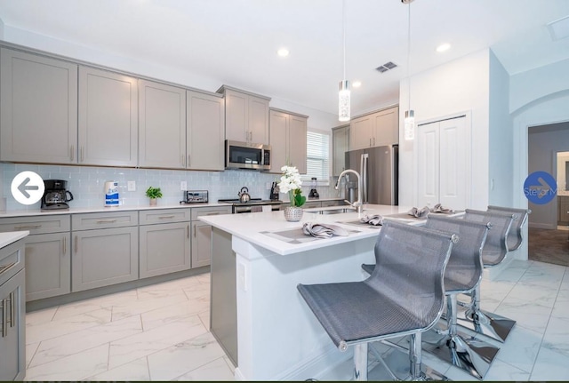 kitchen featuring visible vents, marble finish floor, gray cabinetry, a sink, and appliances with stainless steel finishes