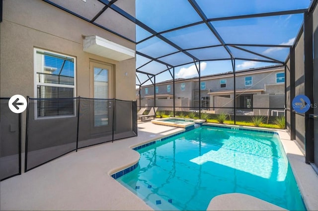 view of pool with glass enclosure, a pool with connected hot tub, and a patio