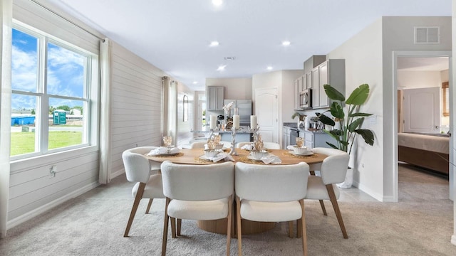 dining room with recessed lighting, visible vents, light colored carpet, and wooden walls