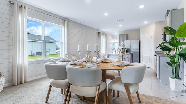 dining space featuring visible vents, light carpet, recessed lighting, wood walls, and light tile patterned floors