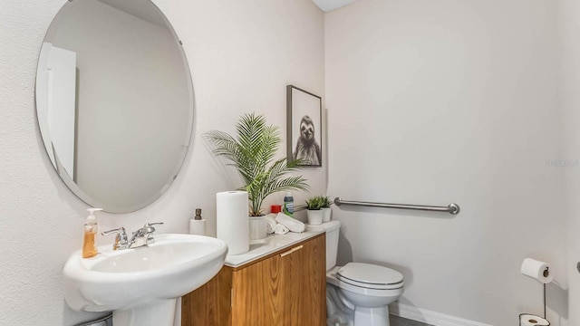 bathroom featuring toilet, baseboards, and a sink