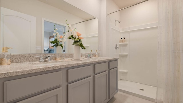 full bathroom with double vanity, a stall shower, and a sink