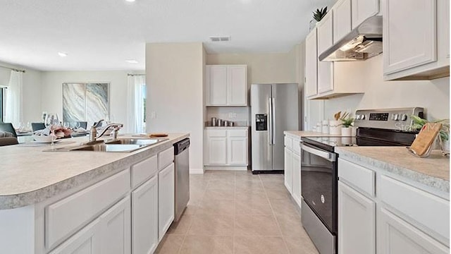 kitchen featuring under cabinet range hood, light countertops, light tile patterned floors, appliances with stainless steel finishes, and a sink