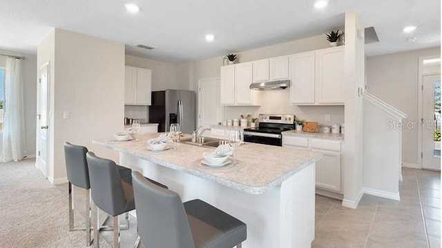 kitchen with a breakfast bar area, light countertops, white cabinets, under cabinet range hood, and appliances with stainless steel finishes