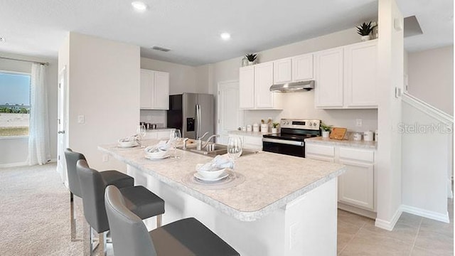 kitchen with under cabinet range hood, light countertops, a kitchen breakfast bar, stainless steel appliances, and white cabinetry