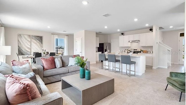 living area with visible vents, recessed lighting, light colored carpet, and baseboards