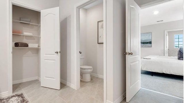 ensuite bathroom featuring tile patterned flooring, toilet, baseboards, and ensuite bathroom