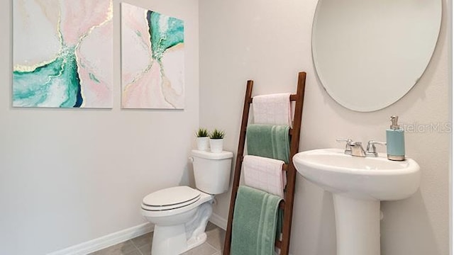 half bathroom featuring tile patterned flooring, toilet, and baseboards