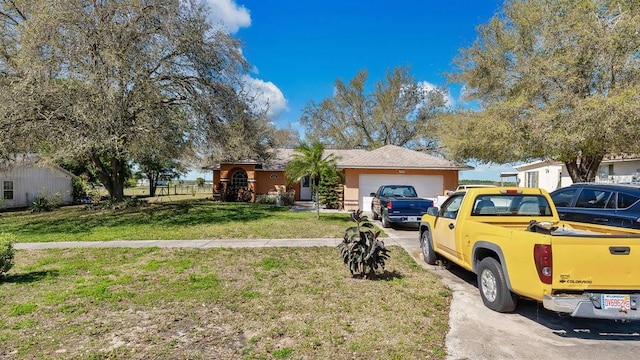 single story home featuring a front lawn, an attached garage, concrete driveway, and stucco siding