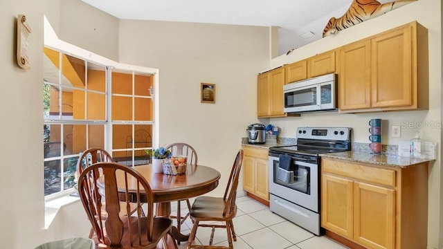 kitchen with light tile patterned floors, light brown cabinets, light stone countertops, and stainless steel appliances