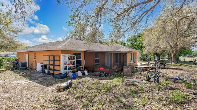 back of house featuring central AC and a shingled roof