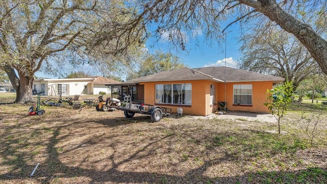 rear view of house featuring stucco siding and fence