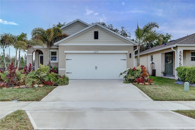 single story home featuring stucco siding, a front yard, an attached garage, and driveway