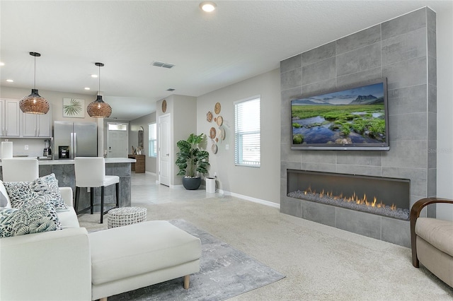 living room featuring visible vents, baseboards, recessed lighting, a fireplace, and a textured ceiling