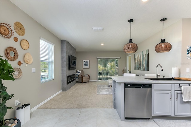 kitchen with visible vents, a tiled fireplace, a sink, stainless steel dishwasher, and light colored carpet