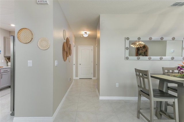 hallway featuring light tile patterned flooring, visible vents, and baseboards