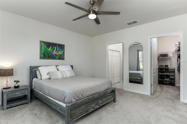 bedroom with visible vents, a spacious closet, a closet, ensuite bathroom, and carpet flooring