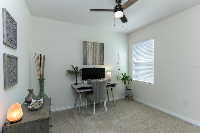 carpeted office space with a ceiling fan and baseboards