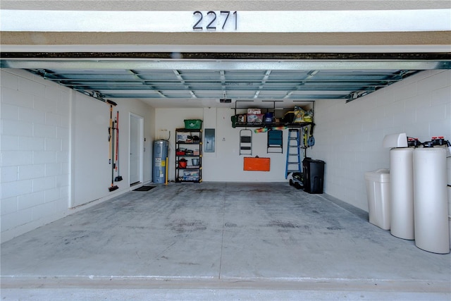 garage with electric panel, electric water heater, and concrete block wall