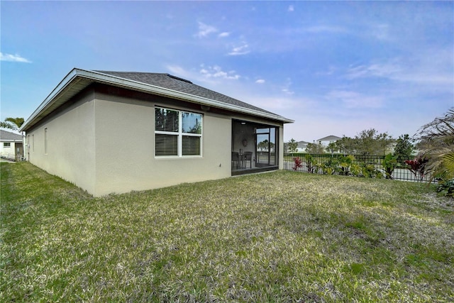 back of property with stucco siding, roof with shingles, a yard, and fence