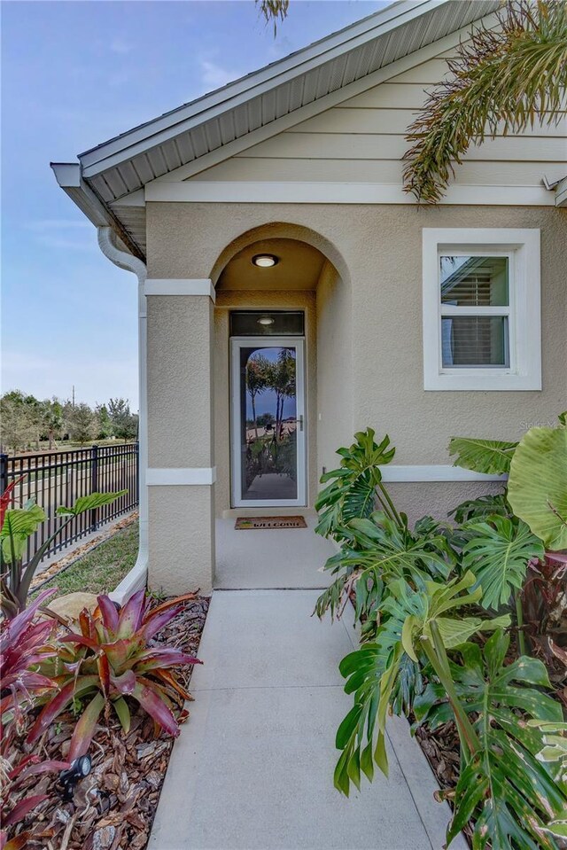 doorway to property with stucco siding and fence