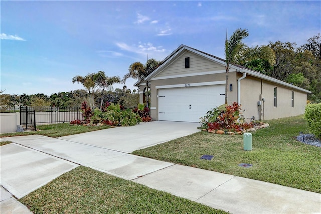 view of front of property featuring stucco siding, driveway, fence, a front yard, and a garage