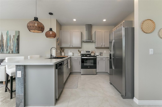 kitchen with gray cabinets, a sink, stainless steel appliances, a peninsula, and wall chimney exhaust hood