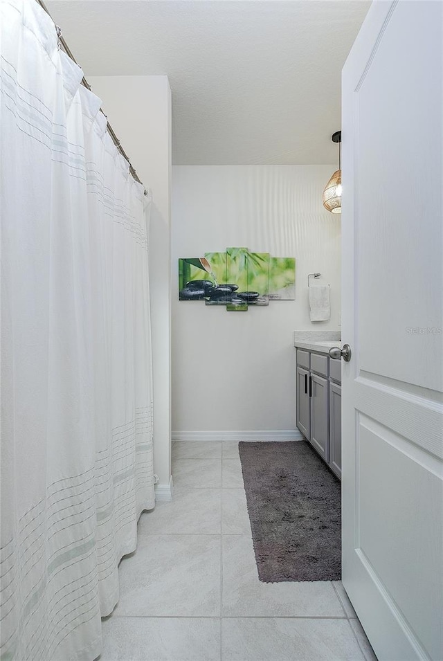 full bathroom with tile patterned floors, curtained shower, baseboards, and vanity