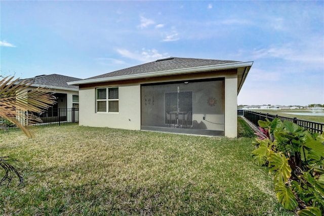 rear view of property featuring a shingled roof, a sunroom, stucco siding, a fenced backyard, and a yard