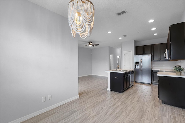 kitchen featuring stainless steel appliances, light wood finished floors, ceiling fan with notable chandelier, and light countertops