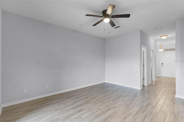 empty room featuring visible vents, ceiling fan, baseboards, and light wood-style floors