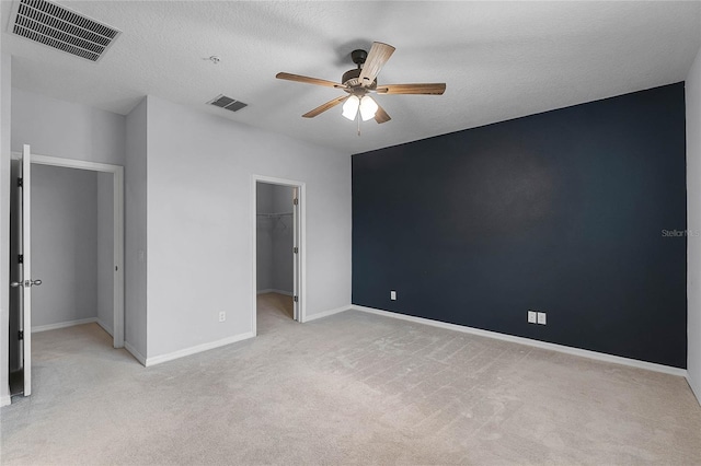 unfurnished bedroom with visible vents, light carpet, baseboards, and a spacious closet