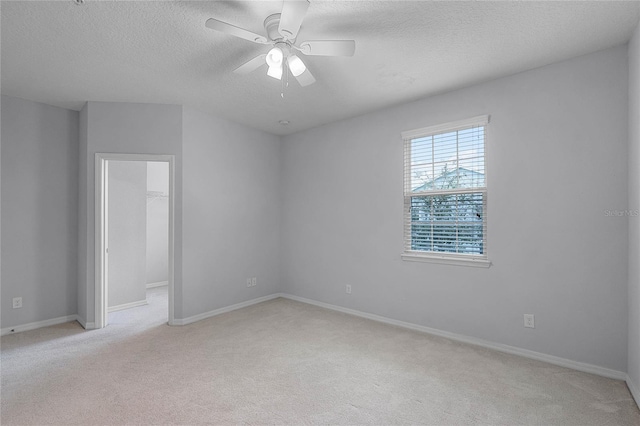 empty room featuring light carpet, baseboards, a textured ceiling, and ceiling fan