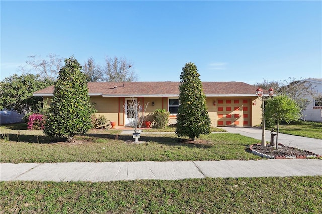 ranch-style home featuring an attached garage, concrete driveway, and a front lawn