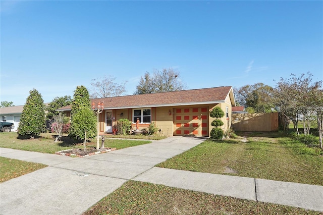 ranch-style home featuring a front yard, fence, a garage, and driveway