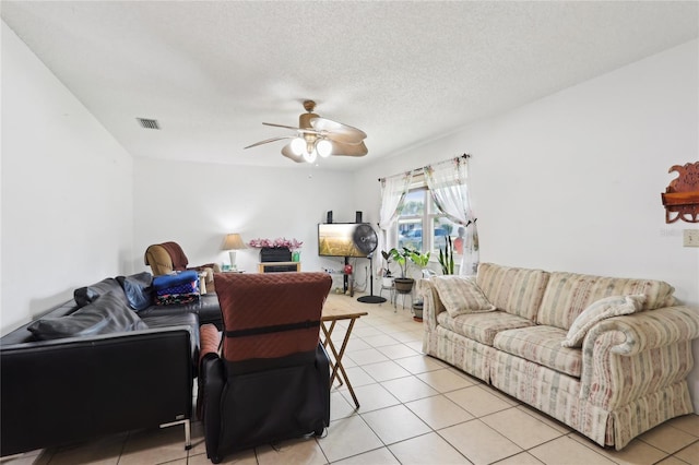 living room with light tile patterned floors, visible vents, a textured ceiling, and a ceiling fan