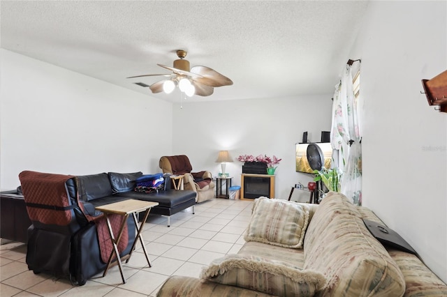 living room featuring light tile patterned floors, a textured ceiling, a glass covered fireplace, and ceiling fan