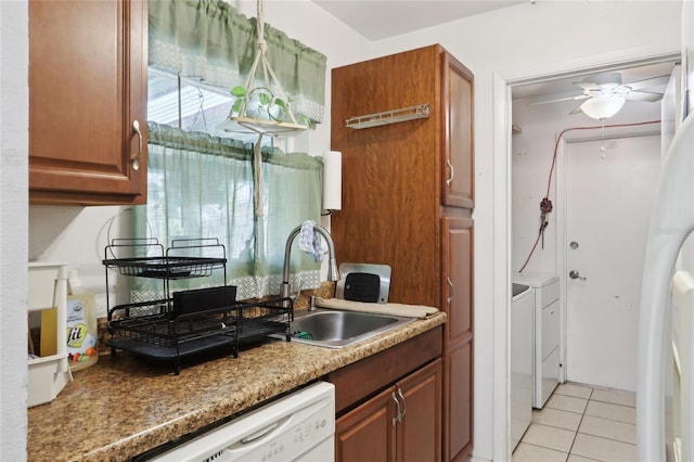 kitchen with brown cabinets, washer and clothes dryer, a sink, light tile patterned floors, and dishwasher