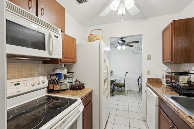 kitchen with white appliances, a ceiling fan, light tile patterned flooring, brown cabinets, and backsplash