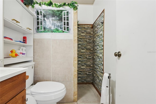 bathroom featuring tile walls, toilet, tiled shower, and vanity