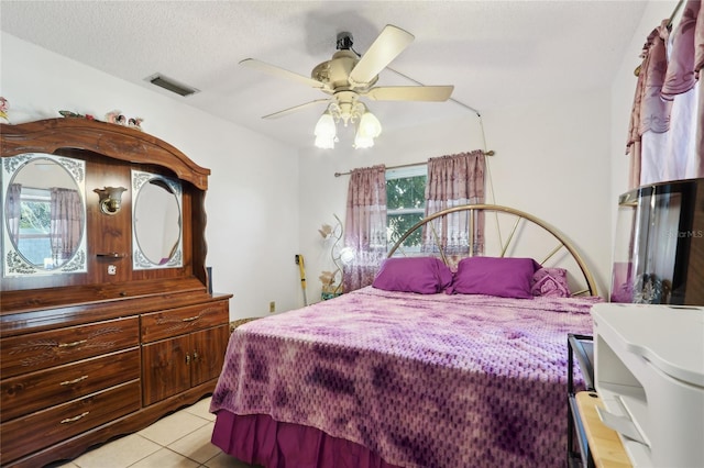 bedroom featuring light tile patterned floors, visible vents, a textured ceiling, and ceiling fan