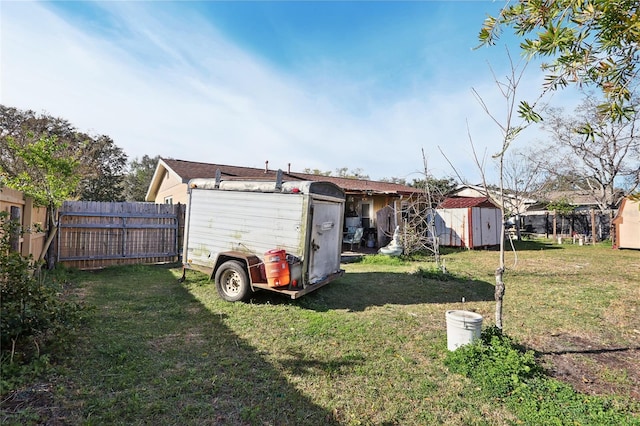 back of property featuring an outdoor structure, a storage shed, a yard, and fence