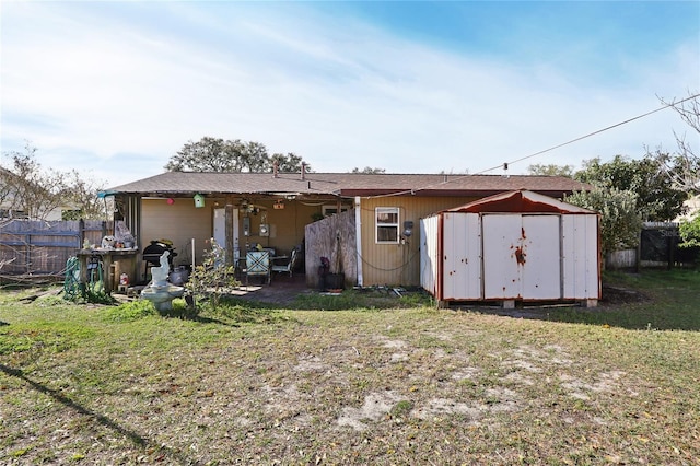 back of house with fence, a shed, a lawn, an outdoor structure, and a patio area