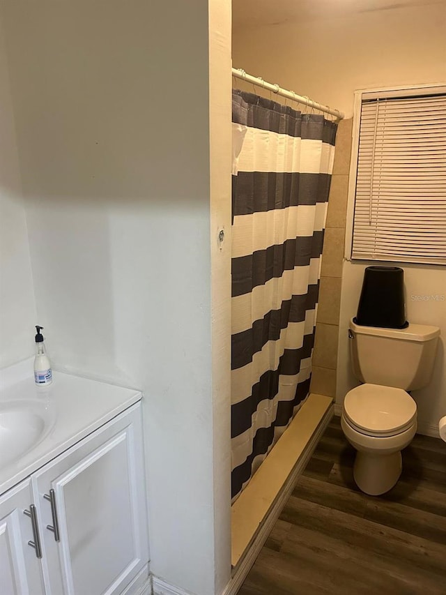 bathroom with curtained shower, toilet, wood finished floors, and vanity